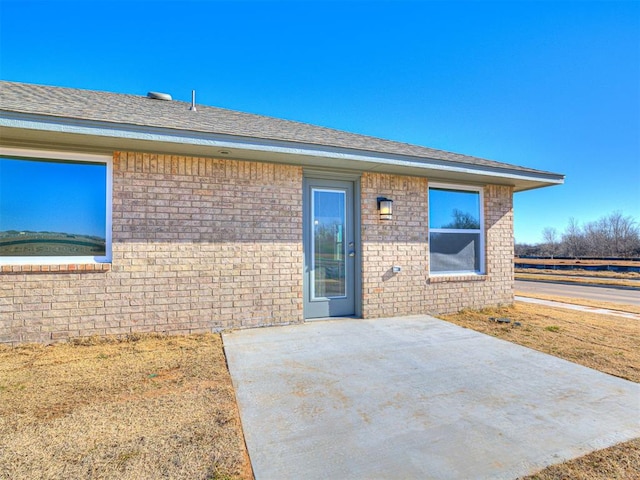 1121 Acacia Creek Dr, Yukon, OK 73099 - view of front facade featuring a patio area, brick siding, fence, and roof with shingles
