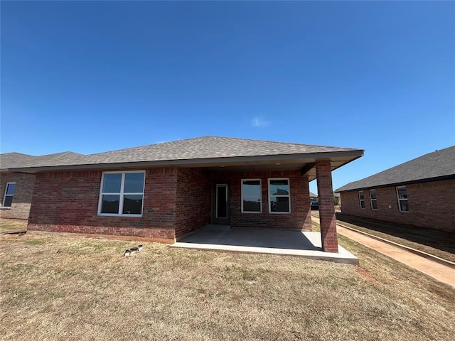 18121 Austin Ct, Edmond, OK 73012 - back of house with brick siding, a patio, a yard, and a shingled roof