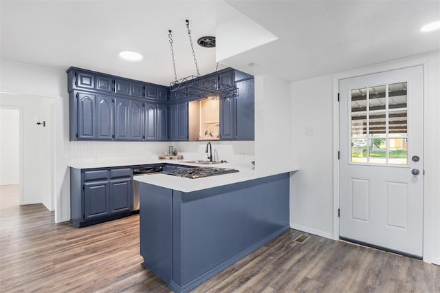 kitchen featuring blue cabinetry, a sink, dark wood-type flooring, and light countertops