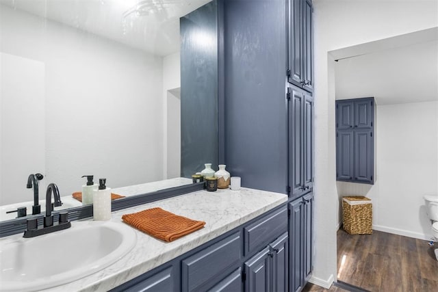 bathroom featuring vanity, wood finished floors, toilet, and baseboards