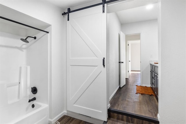 full bath featuring wood finished floors, baseboards, shower / tub combination, and vanity