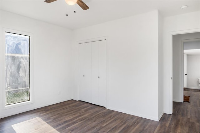 unfurnished bedroom with dark wood-type flooring, multiple windows, and baseboards
