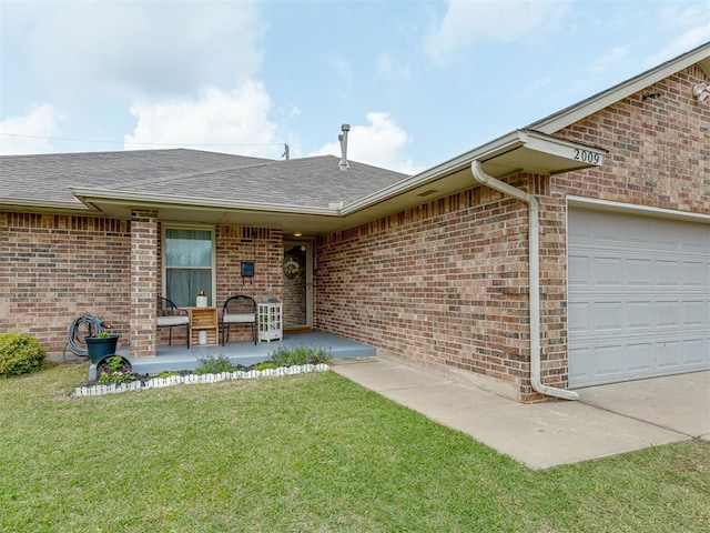 2009 Astoria Dr, Moore, OK 73160 - view of exterior entry with a yard, an attached garage, roof with shingles, and brick siding