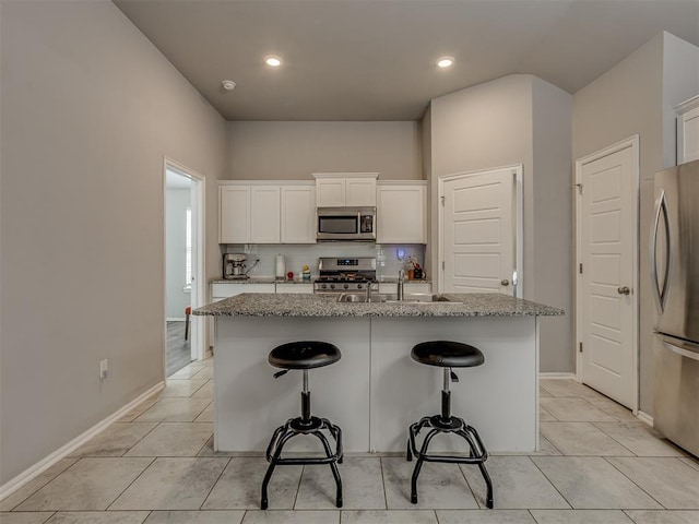 9120 SW 46th St, Oklahoma City, OK 73179 - kitchen featuring stainless steel appliances, a sink, a kitchen breakfast bar, an island with sink, and light stone countertops