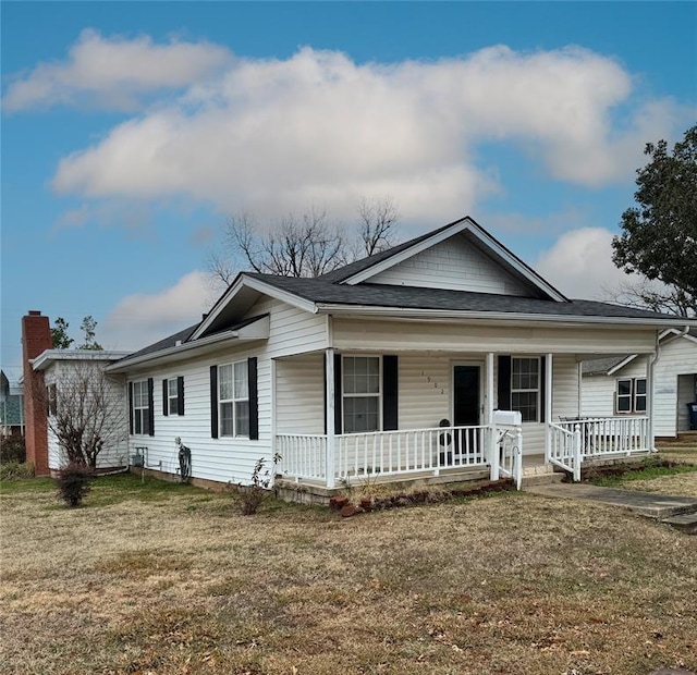 view of front of property with a porch, a front yard, and a shingled roof