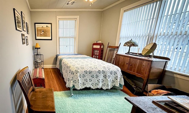 bedroom featuring wood finished floors, crown molding, and baseboards