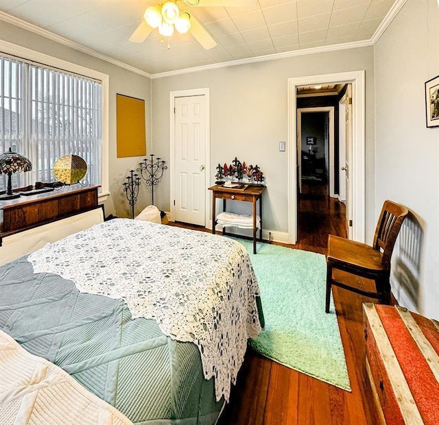bedroom featuring wood finished floors, ornamental molding, ceiling fan, and baseboards
