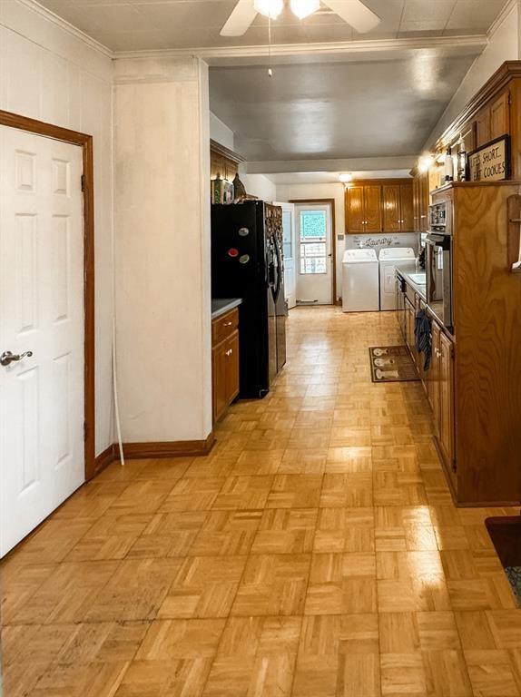 kitchen featuring black appliances, ceiling fan, crown molding, washing machine and clothes dryer, and brown cabinetry