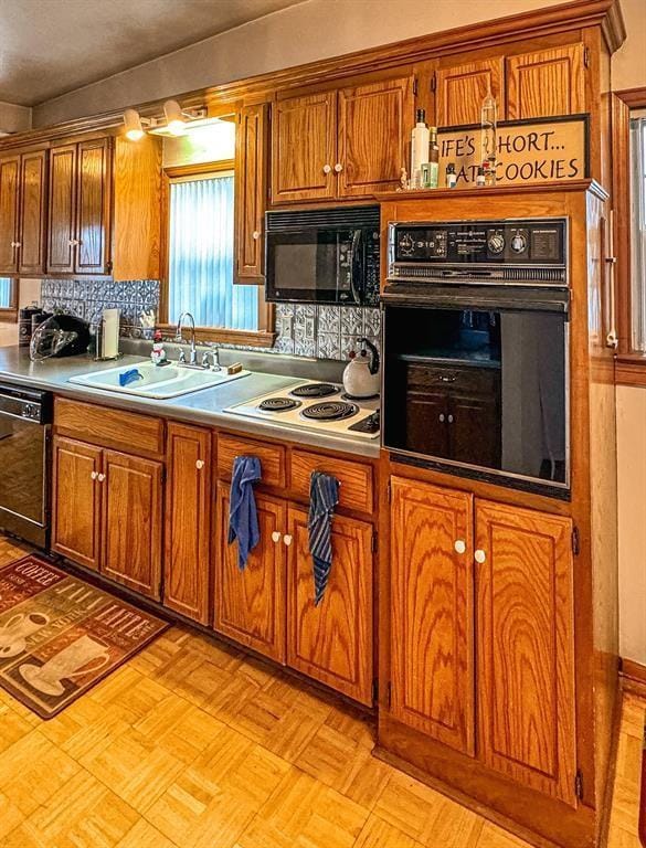 kitchen featuring black appliances, a sink, brown cabinets, tasteful backsplash, and light countertops
