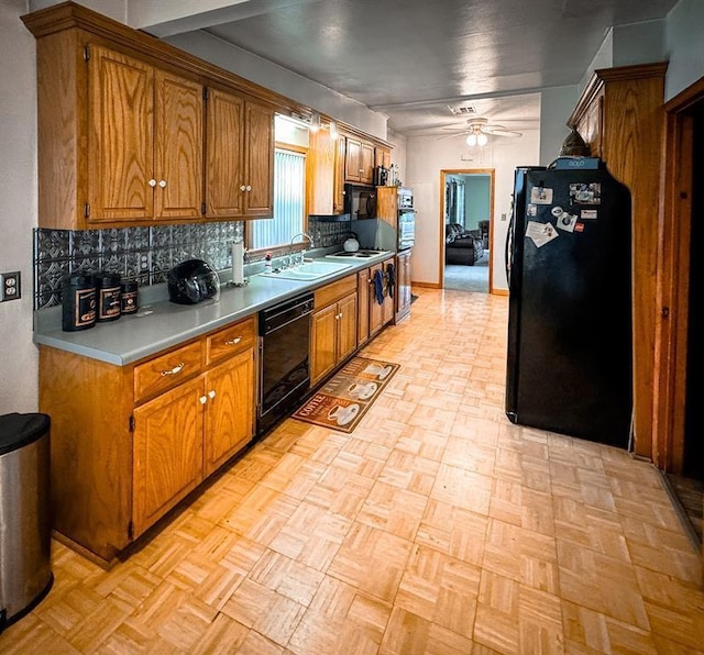 kitchen featuring black appliances, a sink, brown cabinetry, backsplash, and ceiling fan