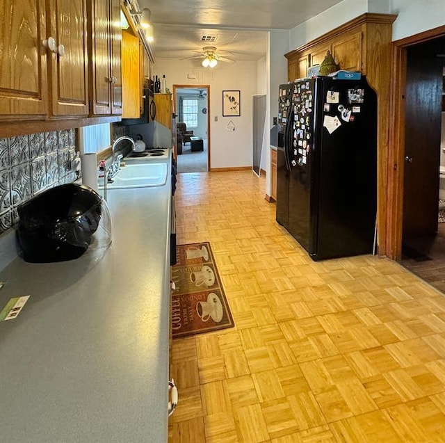 kitchen featuring black fridge, ceiling fan, brown cabinetry, and a sink