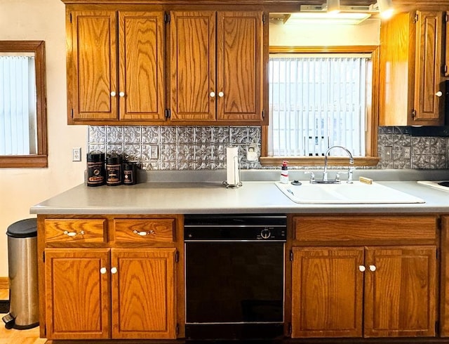 kitchen with a sink, black dishwasher, decorative backsplash, and light countertops