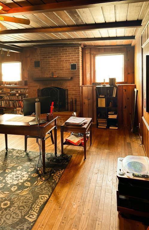 sitting room featuring a fireplace, wood-type flooring, wooden ceiling, a ceiling fan, and beamed ceiling