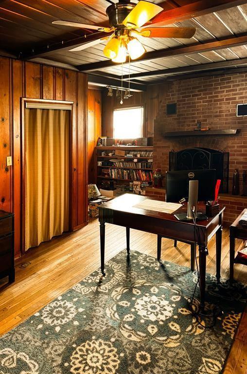 home office featuring light wood-style flooring, a ceiling fan, wood ceiling, wooden walls, and beamed ceiling