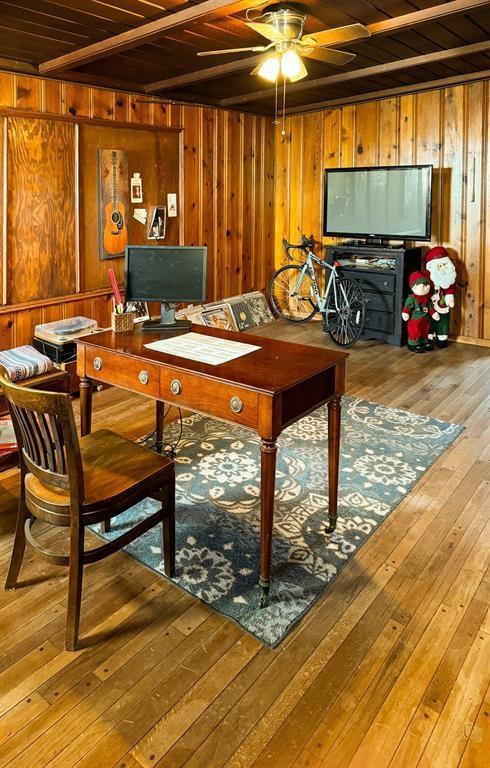 dining area featuring wooden ceiling, light wood-style flooring, a ceiling fan, wooden walls, and an office area