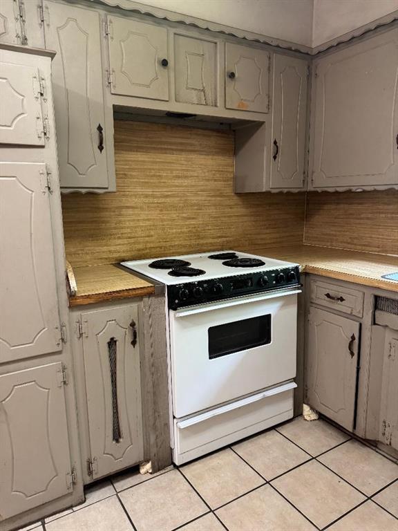 3316 Beechwood Dr, Del City, OK 73115 - kitchen with white electric range, light tile patterned flooring, light countertops, gray cabinetry, and tasteful backsplash