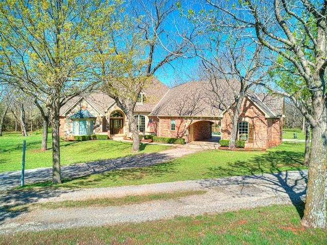 view of front of house with dirt driveway, a front lawn, a carport, and brick siding