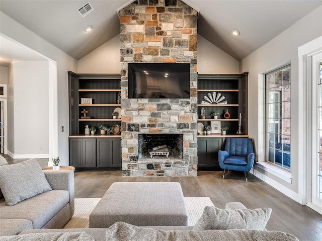 living room with lofted ceiling, a stone fireplace, wood finished floors, and baseboards