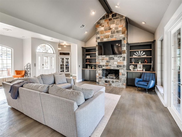 living area featuring wood finished floors, beam ceiling, a fireplace, and high vaulted ceiling