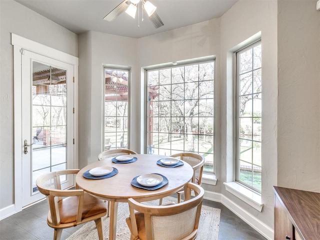 dining space featuring baseboards, dark wood finished floors, and ceiling fan
