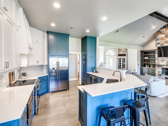 kitchen featuring high quality appliances, a sink, a breakfast bar area, blue cabinets, and open floor plan