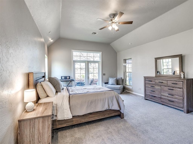 bedroom with lofted ceiling, multiple windows, carpet, a textured wall, and a ceiling fan