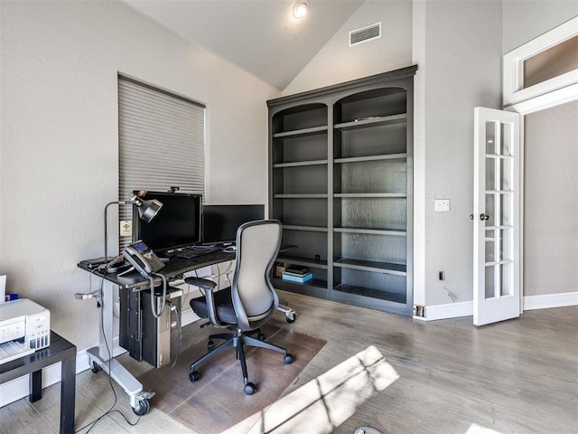 home office featuring vaulted ceiling, wood finished floors, baseboards, and french doors
