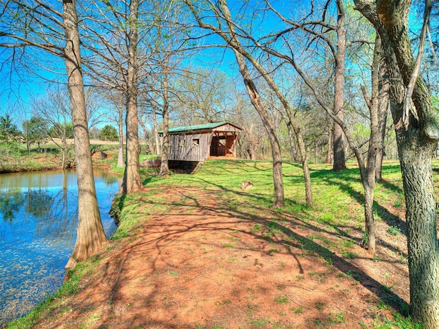 view of yard featuring a water view, an outdoor structure, and a pole building