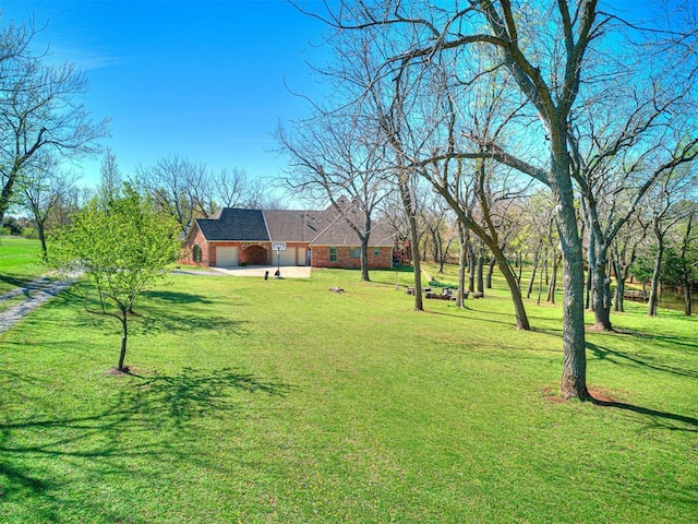 view of green lawn with a garage and driveway