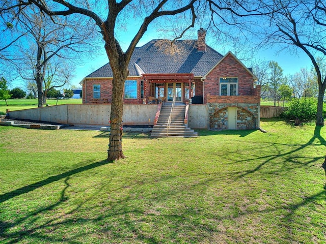 view of front of house with stairs, a chimney, a front lawn, and brick siding