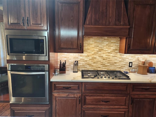 11301 Brockton Pl, Oklahoma City, OK 73162 - kitchen featuring stainless steel appliances, custom range hood, light countertops, decorative backsplash, and dark brown cabinetry