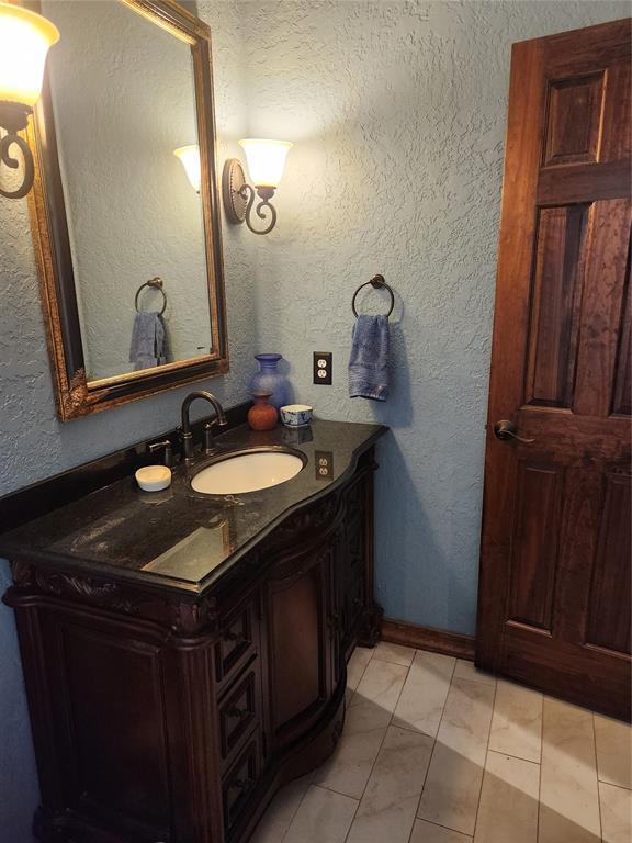 11301 Brockton Pl, Oklahoma City, OK 73162 - bathroom featuring marble look tile flooring, vanity, and a textured wall