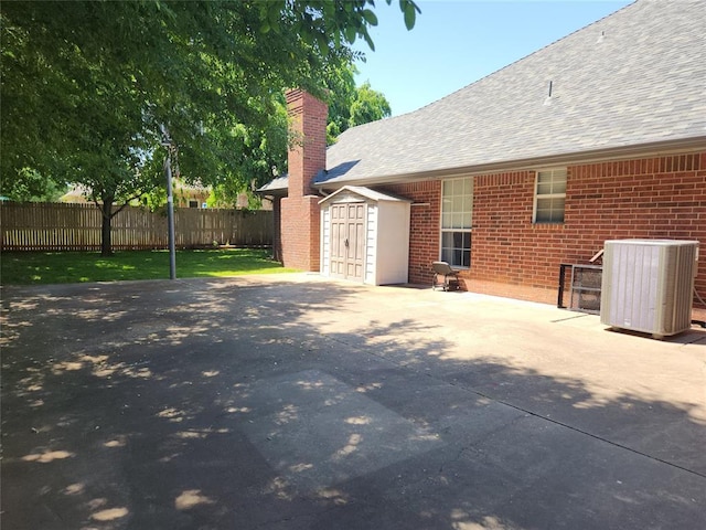 11301 Brockton Pl, Oklahoma City, OK 73162 - view of patio featuring central AC unit, a storage shed, fence, and an outbuilding