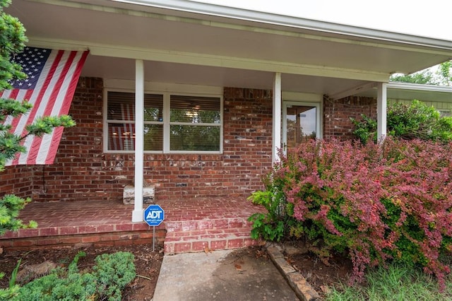 property entrance with brick siding and a porch
