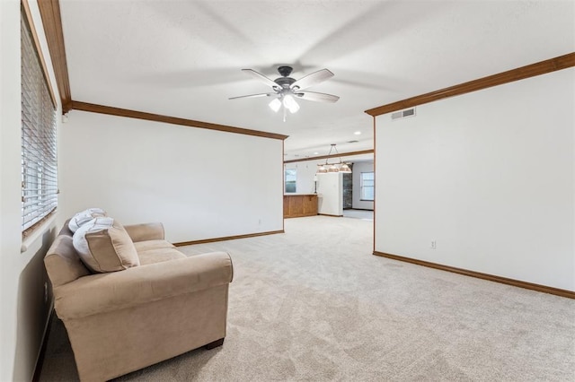 carpeted living room with a ceiling fan, crown molding, and baseboards