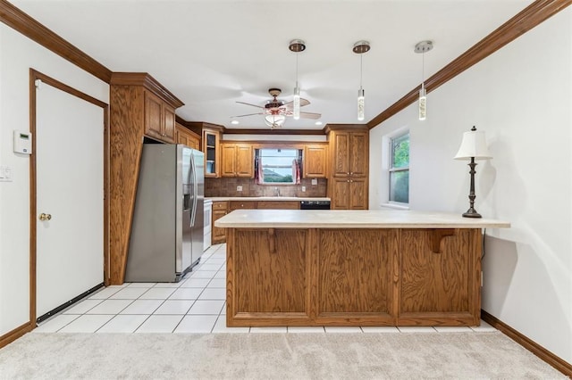 kitchen with stainless steel fridge with ice dispenser, brown cabinets, light countertops, crown molding, and baseboards