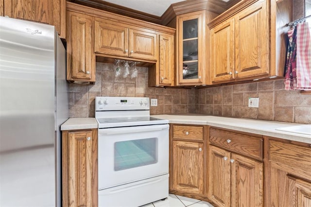 kitchen featuring freestanding refrigerator, white range with electric stovetop, tasteful backsplash, light countertops, and glass insert cabinets