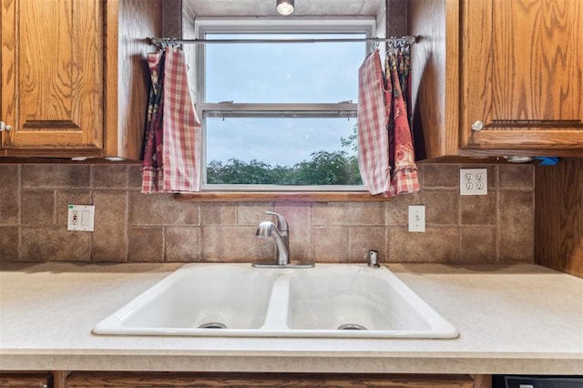 kitchen view of light countertops, a sink, and tasteful backsplash