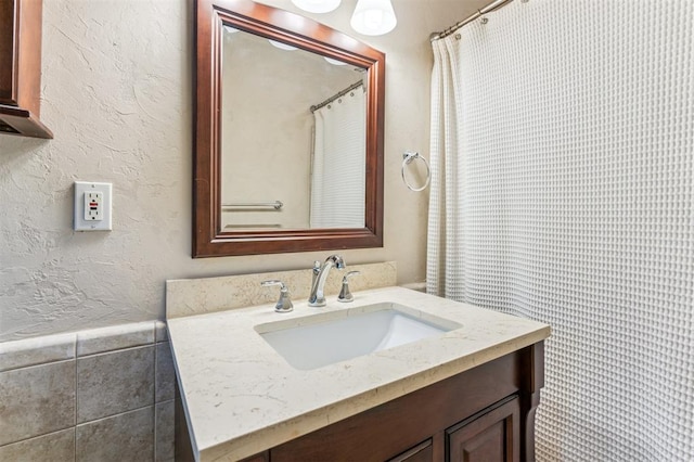 full bathroom featuring vanity and a textured wall