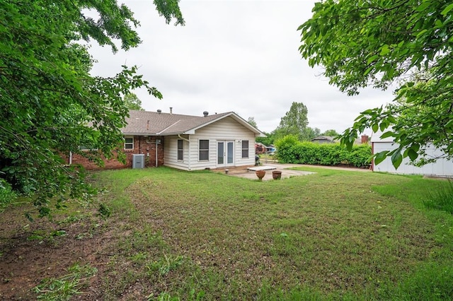 back of house featuring a lawn, a patio area, cooling unit, and an outdoor fire pit