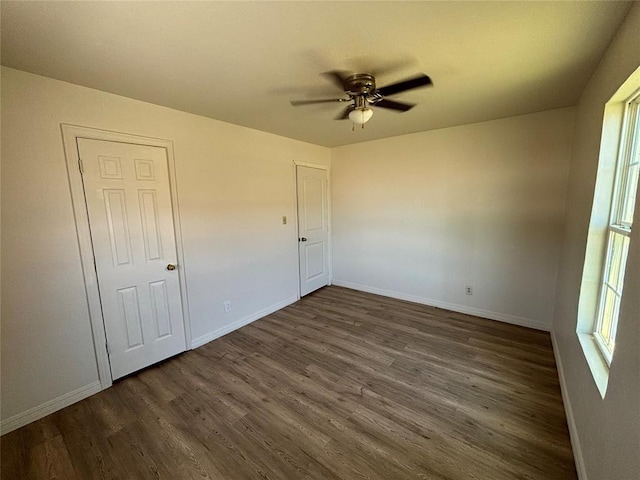 1011 E Sutherland St, Altus, OK 73521 - unfurnished bedroom with dark wood-type flooring, multiple windows, and baseboards