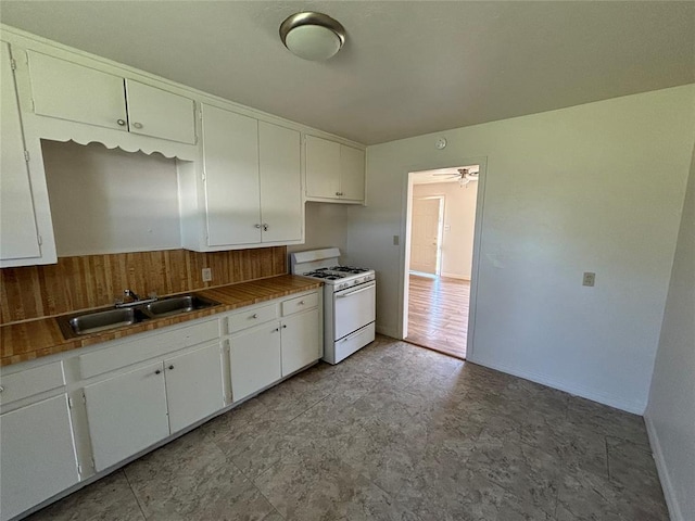 1011 E Sutherland St, Altus, OK 73521 - kitchen with white range with gas stovetop, a sink, white cabinets, and baseboards