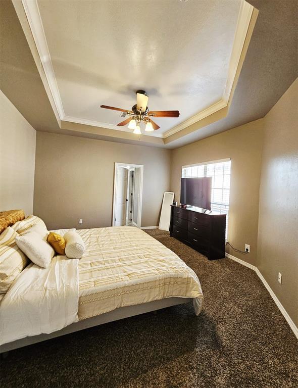 12401 SW 7th St, Yukon, OK 73099 - bedroom featuring a raised ceiling, crown molding, carpet floors, baseboards, and a ceiling fan