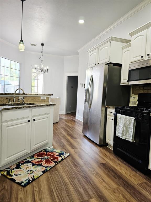 12401 SW 7th St, Yukon, OK 73099 - kitchen with appliances with stainless steel finishes, a sink, ornamental molding, dark wood finished floors, and a chandelier