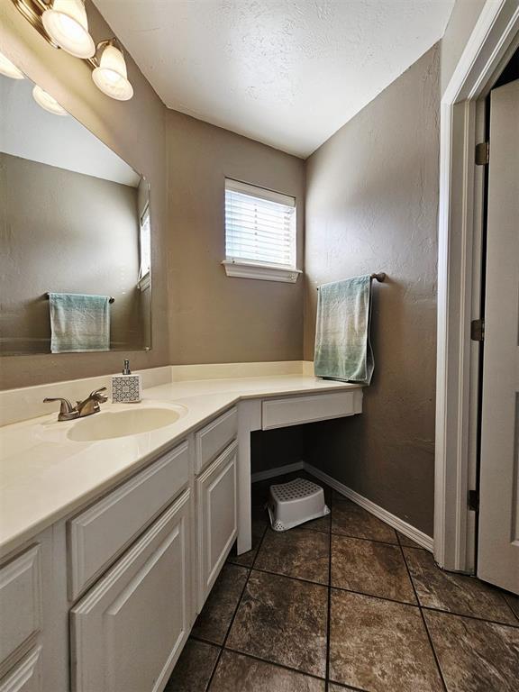12401 SW 7th St, Yukon, OK 73099 - bathroom featuring vanity, a textured ceiling, and baseboards
