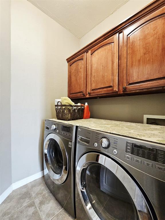 12401 SW 7th St, Yukon, OK 73099 - laundry room with cabinet space, washing machine and clothes dryer, baseboards, and light tile patterned floors