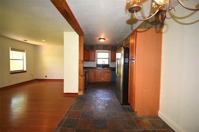 3708 NW 59th St, Oklahoma City, OK 73112 - kitchen with freestanding refrigerator, a sink, baseboards, dark countertops, and brown cabinetry