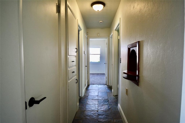 3708 NW 59th St, Oklahoma City, OK 73112 - hallway featuring stone tile floors, baseboards, and a textured wall