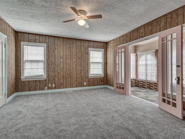 2617 NW 23rd St, Oklahoma City, OK 73107 - spare room with a textured ceiling, a ceiling fan, carpet floors, and wood walls