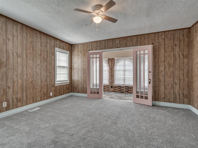 2617 NW 23rd St, Oklahoma City, OK 73107 - empty room with ceiling fan, a textured ceiling, wooden walls, carpet, and baseboards
